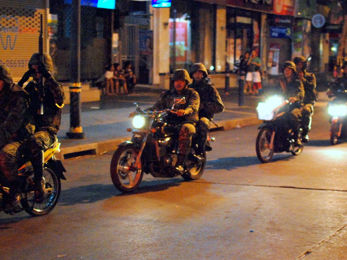 A motorbike taxi rider waiting for a fare on a Dili street corner